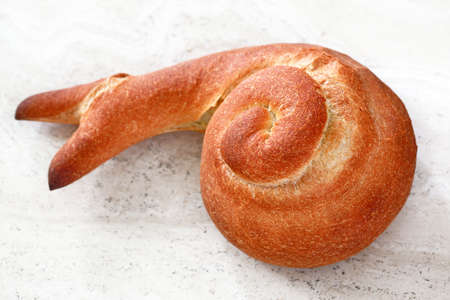 Bread: French bread in the shape of a snail on stone counter-topの写真素材