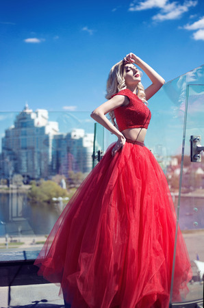 beautiful young girl on the roof of a building in a red lush dress. fashion lookの写真素材