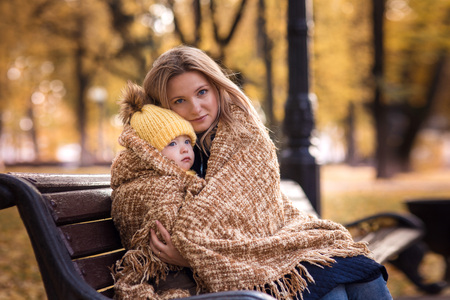 cute little boy with her mother walking in the autumn in the park in the yellow foliage and sitting in a rug. lovely familyの写真素材
