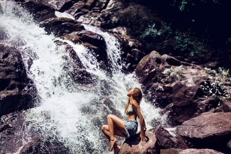 beautiful attractive girl under the sun on a waterfall. tropical beautyの写真素材