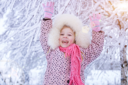 portrait of a girl in the winter with the sun in a fur hat. joyful girl, sunny winterの写真素材