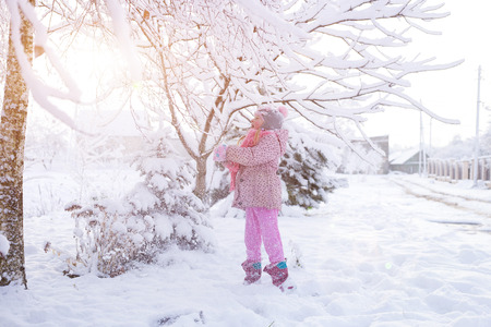 portrait of a girl in the winter with the sun in a fur hat. joyful girl, sunny winterの写真素材
