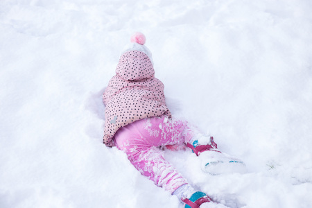 the child is playing in the snow. girl sports and has fun in winterの写真素材