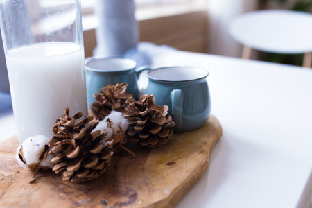 cones of spruce with a mug on a wooden board. cones lie on the background of wood, beautiful Christmas composition in the kitchenの写真素材