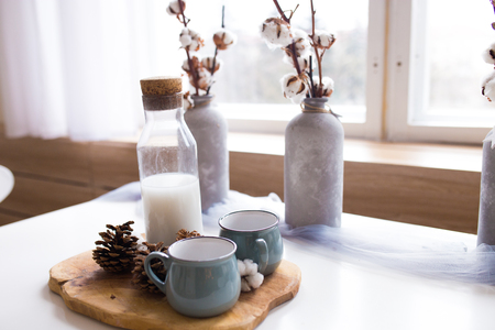 cones of spruce with a mug on a wooden board. cones lie on the background of wood, beautiful Christmas composition in the kitchenの写真素材