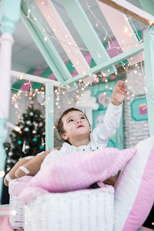 the little boy reaches for the lights. games in the children's room. New Year's lights, children's dreamsの写真素材