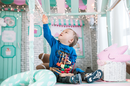 the little boy reaches for the lights. games in the children's room. New Year's lights, children's dreamsの写真素材