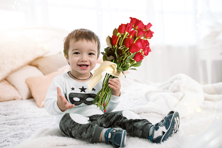 the child is holding a bouquet of flowers. boy and roses are beautiful. a gift from children by March 8 and the day of all lovers lifeの写真素材