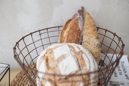 bread in the basket. loaf and baguette in the kitchen, homemade pastries with powder. delicious flour products on the tableの写真素材