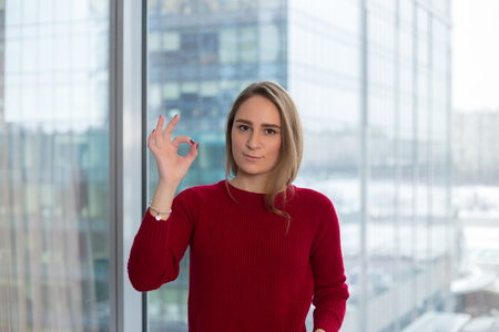 business girl at the window shows a finger that everything is ok. approval from a partner. business negotiation successの写真素材