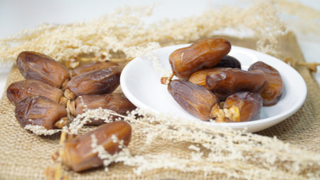 Dates fruit on white plate on sackcloth background. Selective focus.