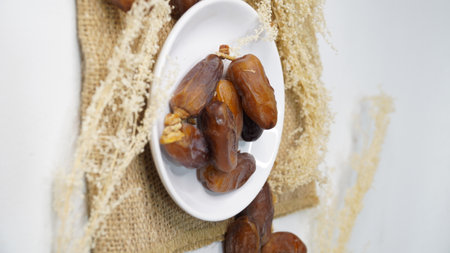 Dates fruit on white plate and burlap sack on white background