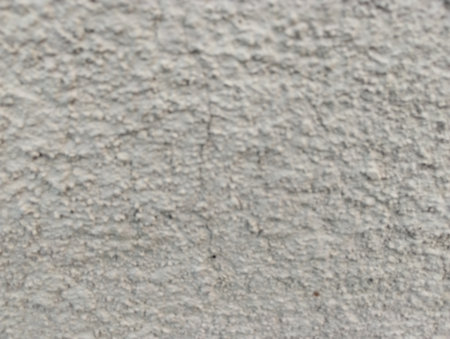Close-up texture of a rough white plaster wall with small bumps and subtle cracks. Ideal for use as a background, surface texture, or design overlay in architectural and graphicの写真素材