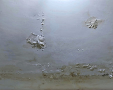 Close-up texture of a ceiling surface damaged by water leakage, showing cracks, stains, and peeling paint. Perfect for backgrounds, grunge textures, or illustrating moistureの写真素材
