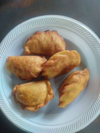 A close-up shot of Panada, a traditional savory fried bread originating from Manado, North Sulawesi, Indonesia. These golden, crescent-shaped pastries are typically filled withの写真素材