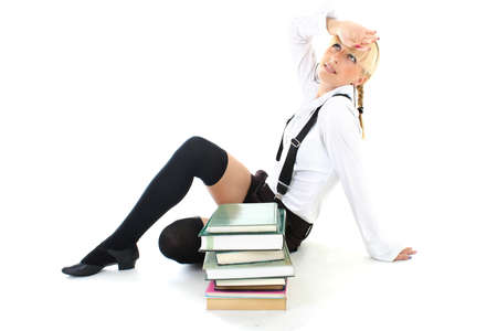 tired schoolgirl in school form sitting with booksの写真素材