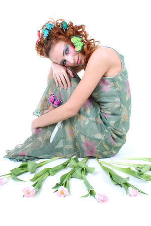Red-haired woman with tulips and butterflies on her head sittingの写真素材