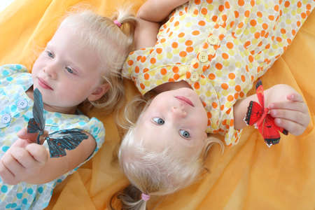little twins playing with butterfliesの写真素材