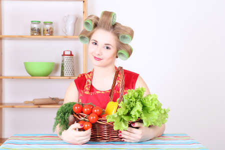 young beautiful woman with hair curlers in the kitchenの写真素材