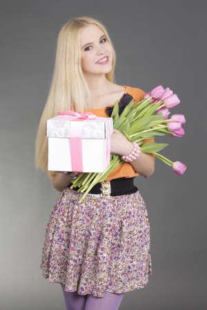portrait of beautiful blondie girl with gift and pink flowers