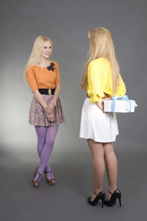 young woman giving a present to her friend for birthdayの写真素材