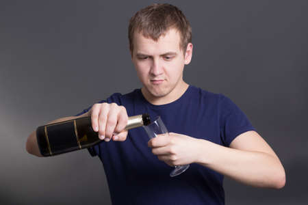 drunk man with bottle of champagne and glass over greyの写真素材