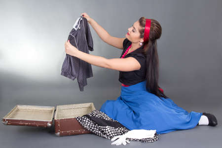 attractive pinup girl packing retro suitcase over greyの写真素材