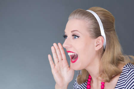 portrait of young attractive pinup girl screaming over greyの写真素材