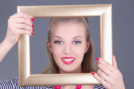 attractive blondie pinup girl in striped dress with photo frame over greyの写真素材