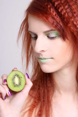 young attractive redhaired girl with kiwi  over whiteの写真素材