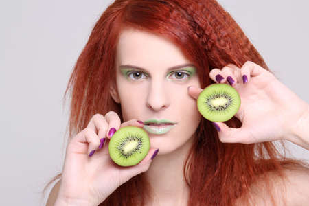 portrait of redhaired girl with kiwi over whiteの写真素材