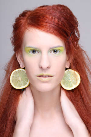 portrait of redhaired girl with lemon slices in earsの写真素材