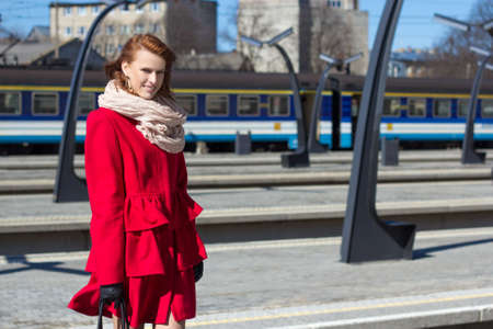 young woman waiting train on the platform of railway stationの写真素材