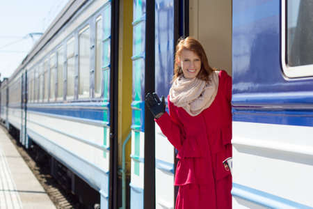 young beautiful redhaired woman near a trainの写真素材