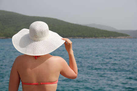 slim woman in swimsuit and white hat on the beachの写真素材