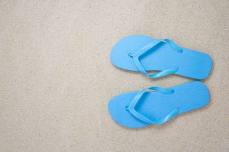 blue flip flops on the white beach sand with copyspaceの写真素材