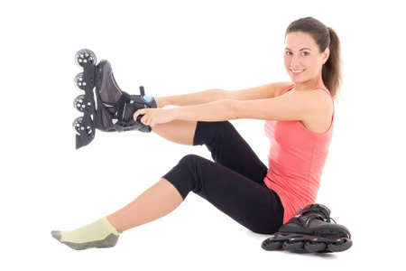 young brunette woman sitting and putting on skates isolated on white