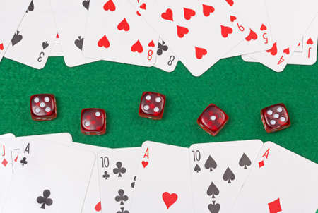 close up of playing cards and red dices on the green casino table