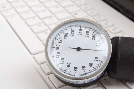 close up of sphygmomanometer on white notebook keyboardの写真素材