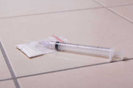 drug syringe and heroin powder on tiled floorの写真素材