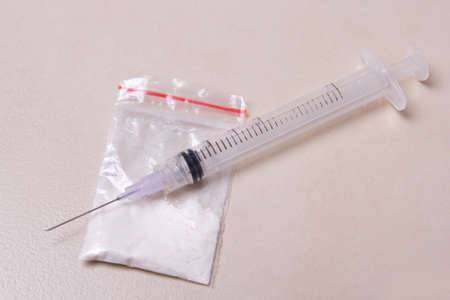 drug syringe and heroin powder in pack on tiled floor