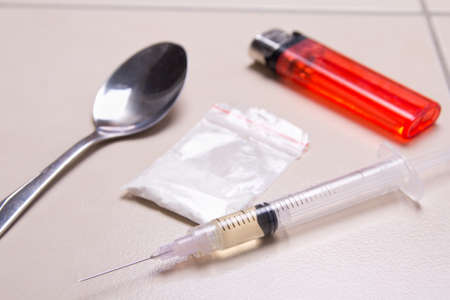 close up of drug syringe, heroin powder, spoon and lighter on tiled floor in bathroomの写真素材