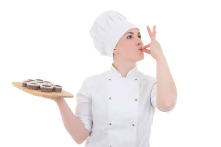portrait of young attractive cook woman in uniform with chocolate muffins isolated on white backgroundの写真素材
