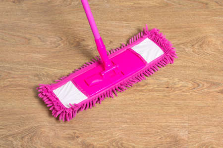 cleaning wooden floor with wet pink mop