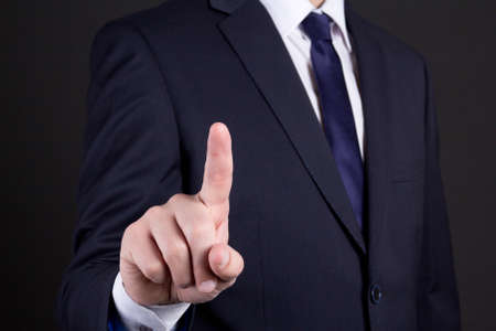 businessman hand pressing an imaginary button on over dark backgroundの写真素材