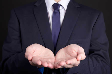 business man holding hand presenting product over dark backgroundの写真素材