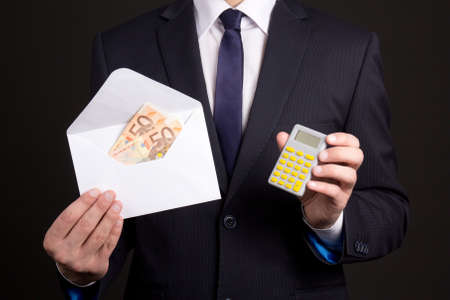young business man holding envelope with money and calculatorの写真素材