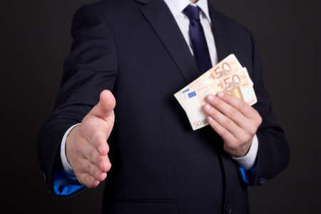 bribery concept - man in suit with euro banknotes ready to handshakeの写真素材