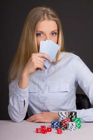 young attractive woman playing poker over grey background