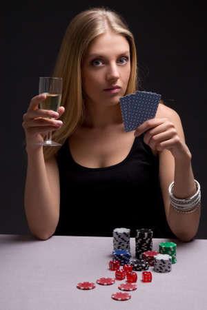 young beautiful blond woman with glass of champagne playing pokerの写真素材